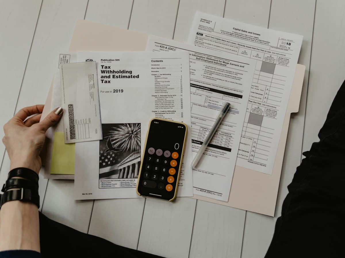 Billing specialist reviewing insurance claim forms and payment records with a calculator